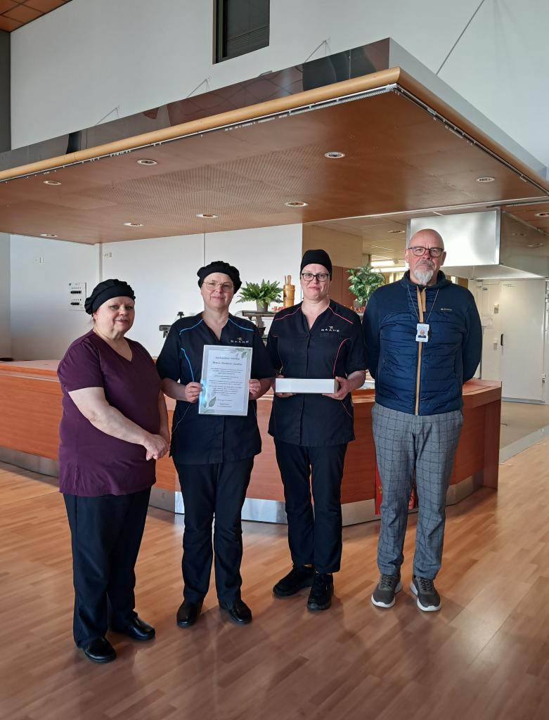 Kuvassa neljä henkilöä seisoo rivissä.