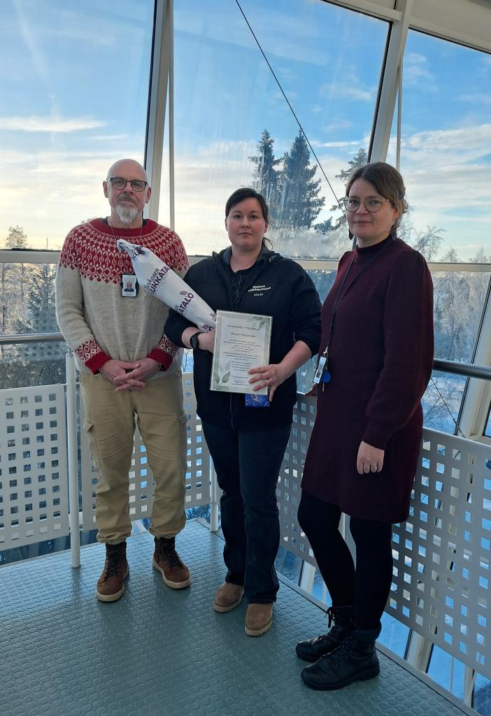 Kuvassa kolme ihmistä seisoo talvisessa maisemassa.