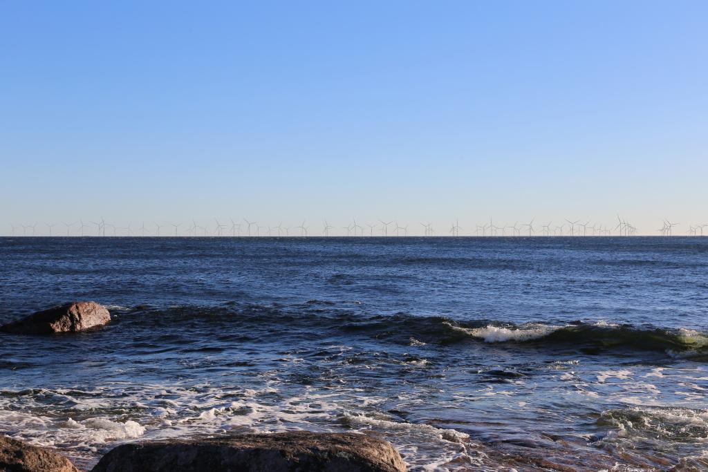 Havainnekuvassa tuulivoimaloita kaukana merellä.