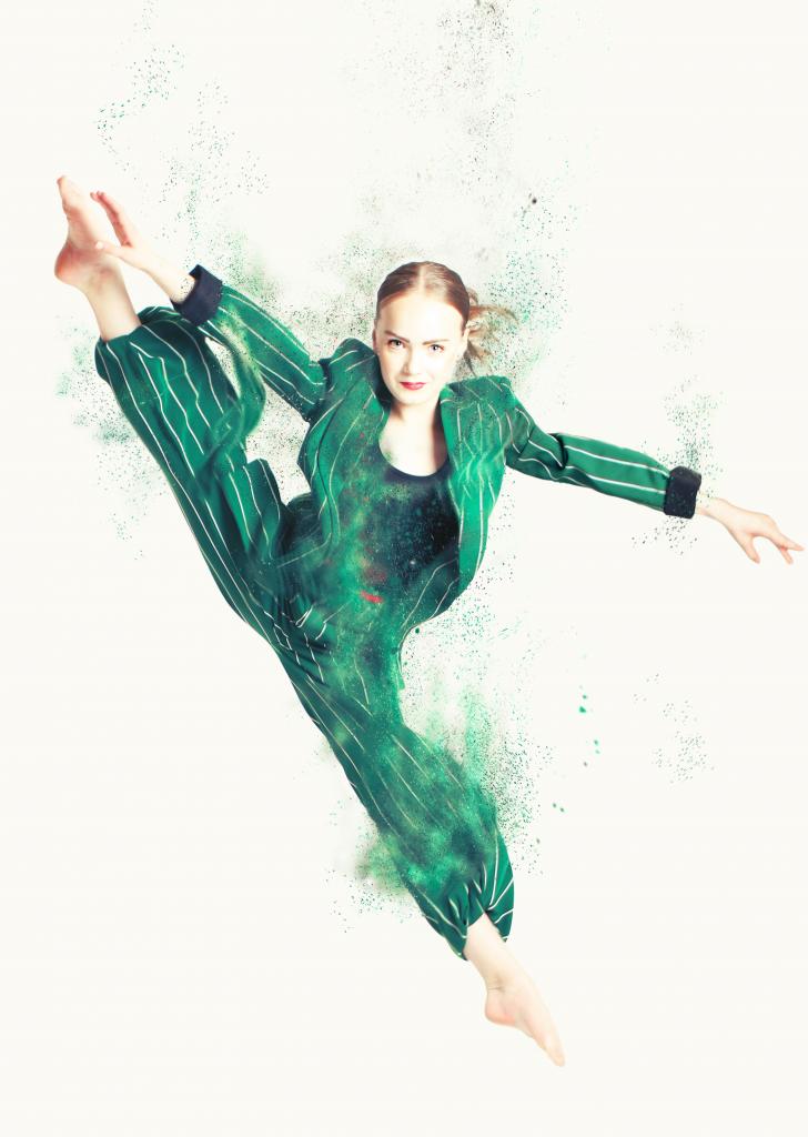 Nuori tanssija vihreässä housupuvussa kädet ja jalka ojennettuna. 