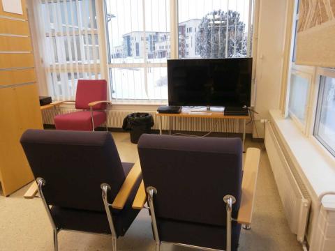 Edessä kaksi nojatuolia, joiden takana televisio.