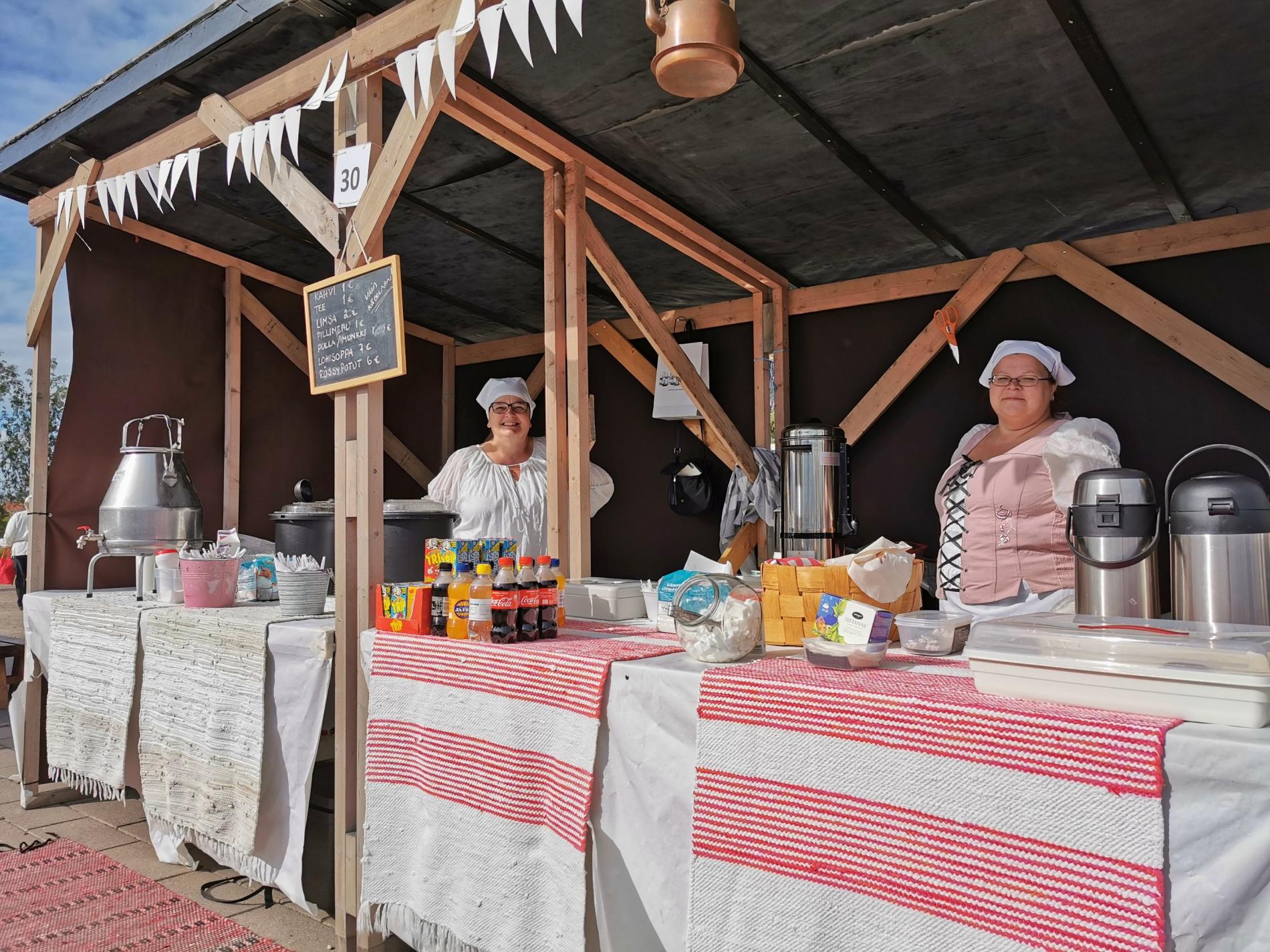 Vanhan ajan tyyliin pukeutuneita markkinamyyjiä kojussaan.