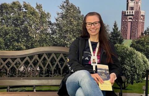 Johanna istuu puiston penkillä Raahen maisemakulisseissa.