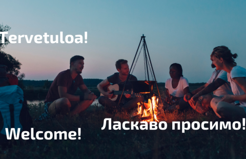 A campfire around which people spend time. Around the campfire, the text "Welcome!" in Finnish, English and Ukrainian