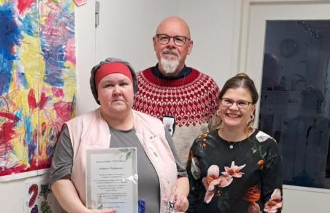 Kuvassa kolme henkilöä hymyilee kameralle.