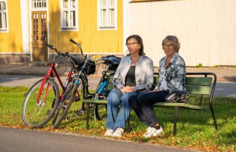 Kaksi henkilöä istuu puiston penkillä.