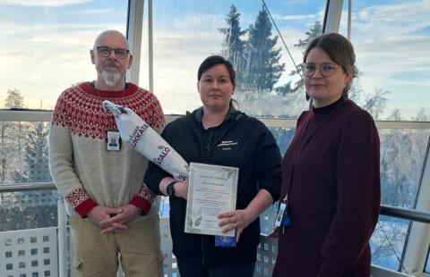 Kuvassa kolme ihmistä seisoo talvisessa maisemassa.