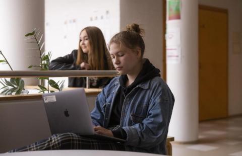 Kaksi opiskelijaa istumassa koulun aulassa.
