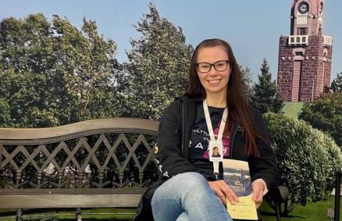 Johanna istuu puiston penkillä Raahen maisemakulisseissa.