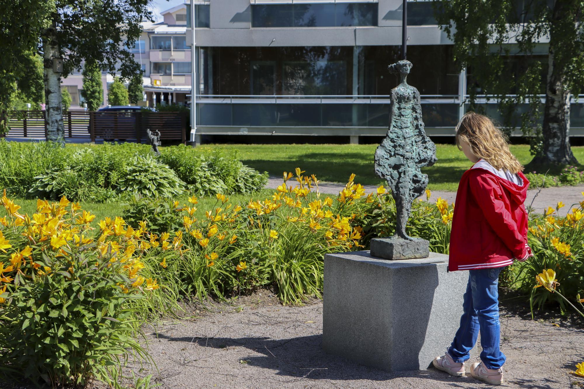 Barnet tittar på statyer i parken.
